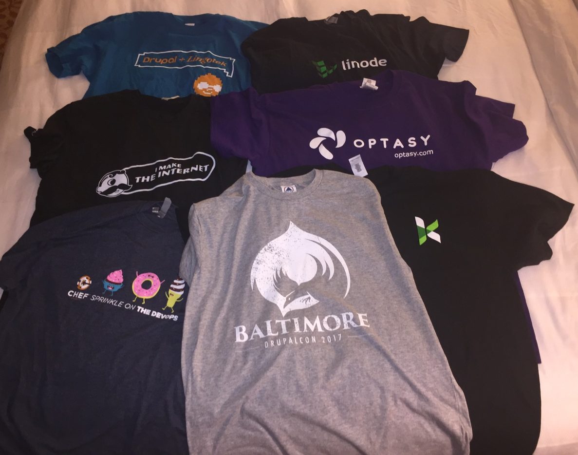A picture of a pile of t-shirts on a bed